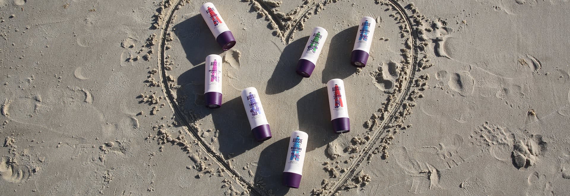 A photo of Aussie products lying on a beach in the middle of heart made in the sand