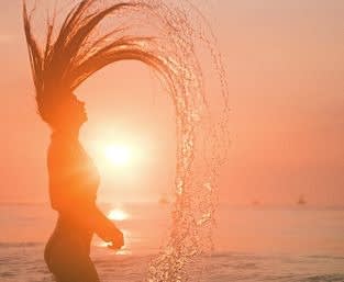 Picture of a woman splashing water with hair during sunset