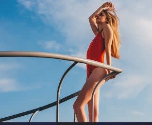 Picture of a woman with blonde hair in red bathing suit leaning on the railing