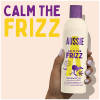 A picture of calm the frizz shampoo Bottle in hand with claim: calm the frizz