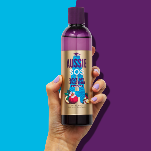 An image of Aussie 1 InHand SHAMPOO holded in hand on puple-blue background