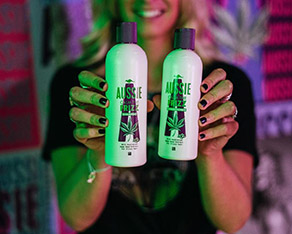 Picture of a smiling woman holding two bottles of shampoo