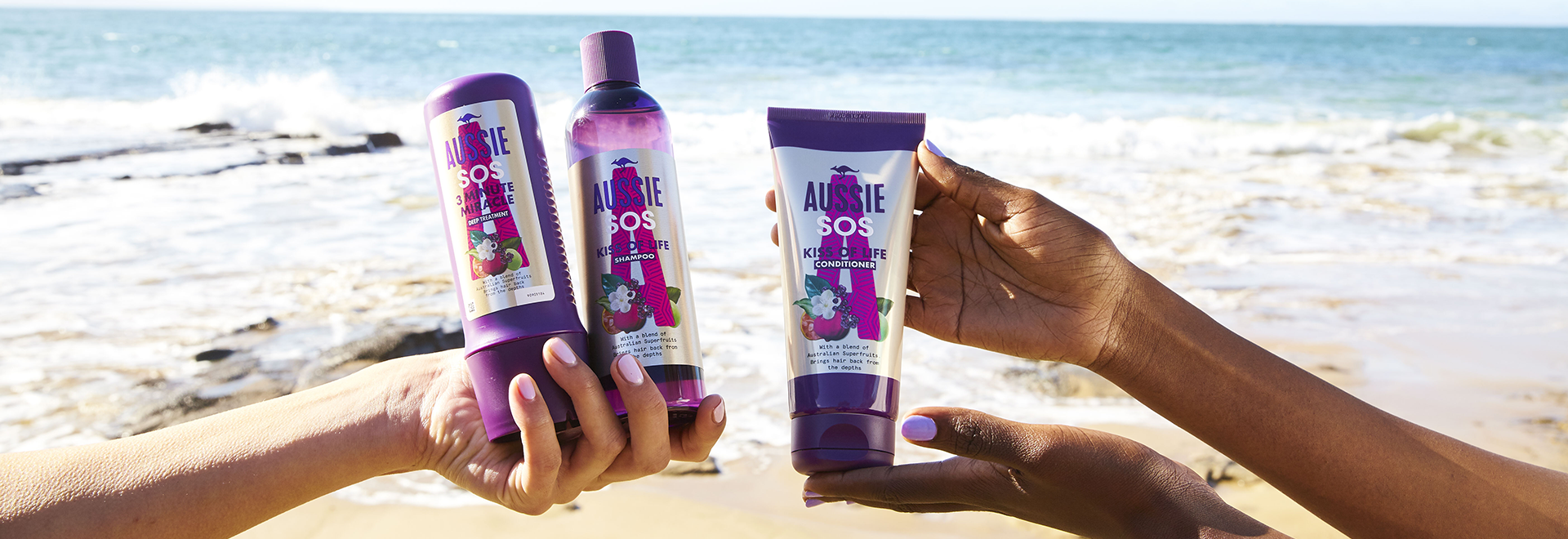 A photo of Aussie SOS Kiss of Life products holded in hands on the beach environment 